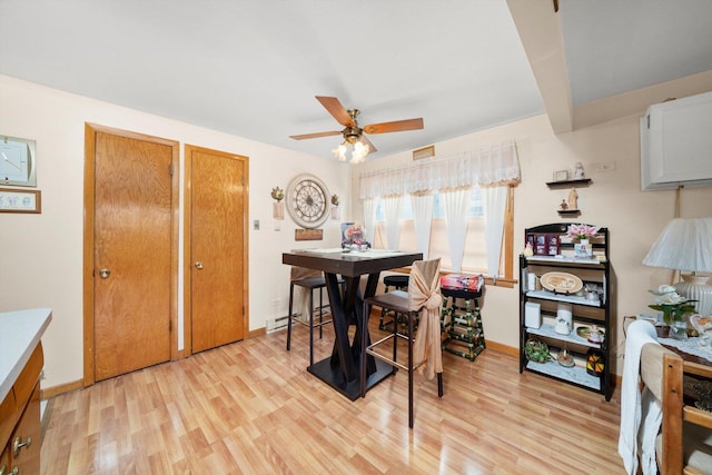 dining room featuring light wood-style floors, baseboards, and a ceiling fan