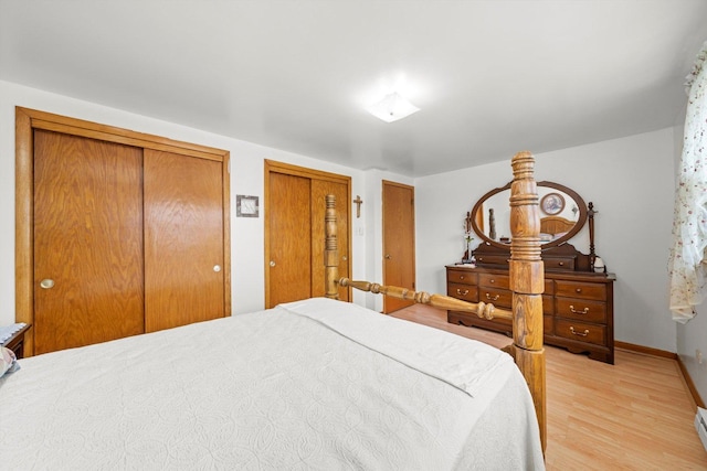 bedroom featuring light wood-type flooring, baseboards, and two closets