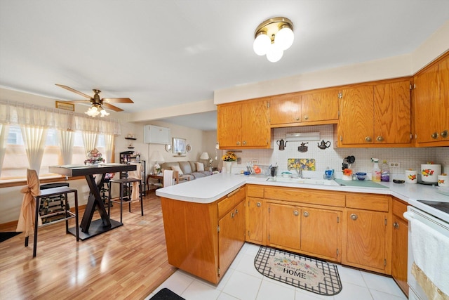 kitchen featuring a peninsula, backsplash, a sink, and light countertops