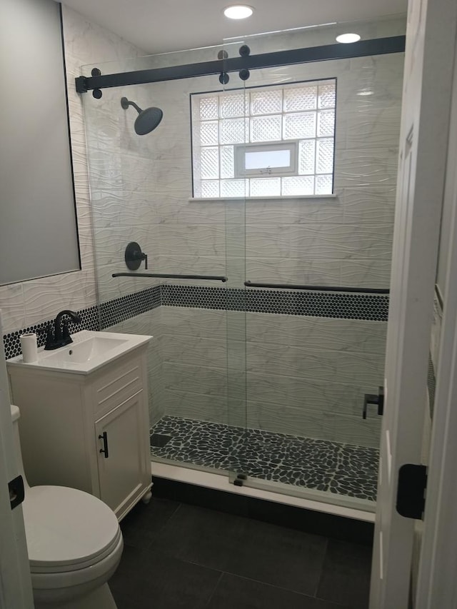 bathroom with a stall shower, vanity, toilet, and tile patterned floors