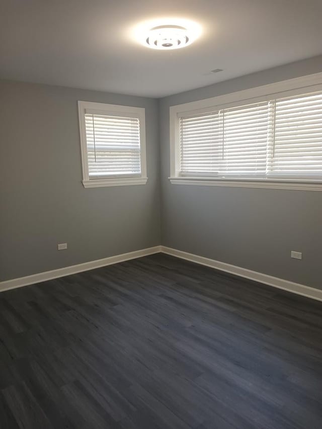 spare room featuring dark wood finished floors and baseboards