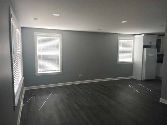 spare room with dark wood-type flooring and baseboards