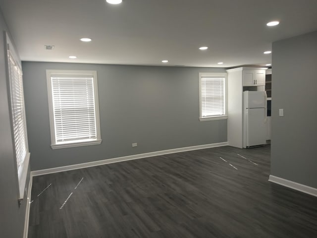 empty room featuring recessed lighting, dark wood-style flooring, visible vents, and baseboards