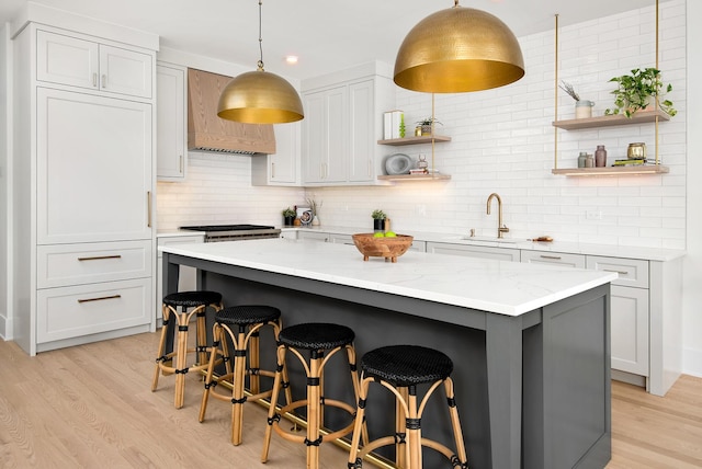 kitchen featuring tasteful backsplash, a sink, light wood finished floors, and open shelves