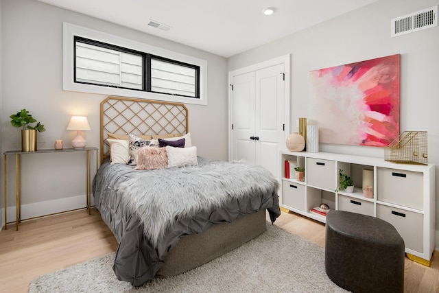 bedroom featuring light wood finished floors, baseboards, visible vents, and a closet