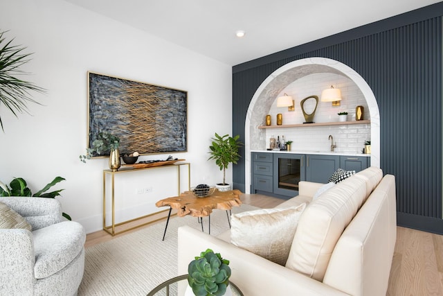 living room featuring light wood-style flooring, wet bar, and beverage cooler