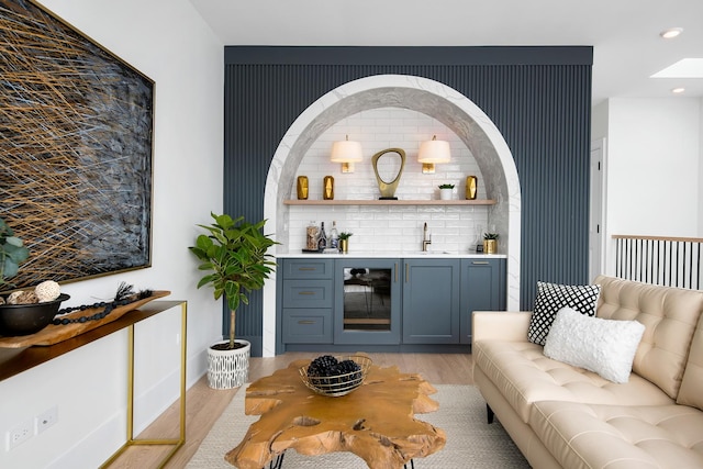 bar with a dry bar, beverage cooler, light wood-style flooring, a sink, and recessed lighting