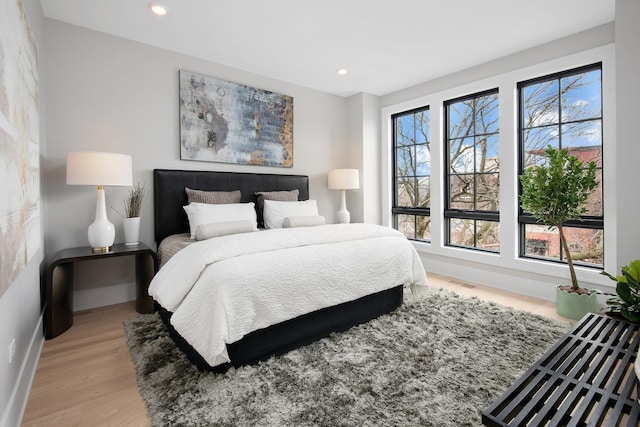 bedroom with baseboards, wood finished floors, visible vents, and recessed lighting