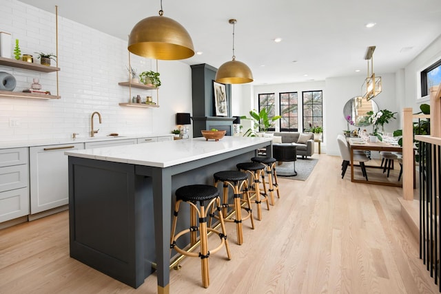 kitchen featuring a center island, light wood finished floors, open shelves, tasteful backsplash, and dishwasher