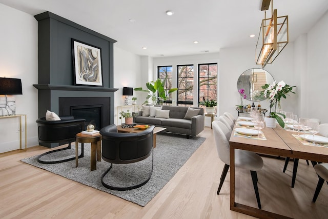 living room featuring a glass covered fireplace, wood finished floors, and recessed lighting