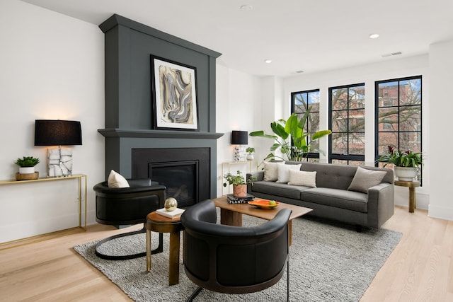 sitting room featuring baseboards, visible vents, a glass covered fireplace, wood finished floors, and recessed lighting