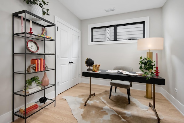 home office featuring visible vents, light wood-style flooring, and baseboards