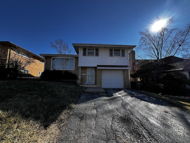 tri-level home featuring aphalt driveway, brick siding, and an attached garage