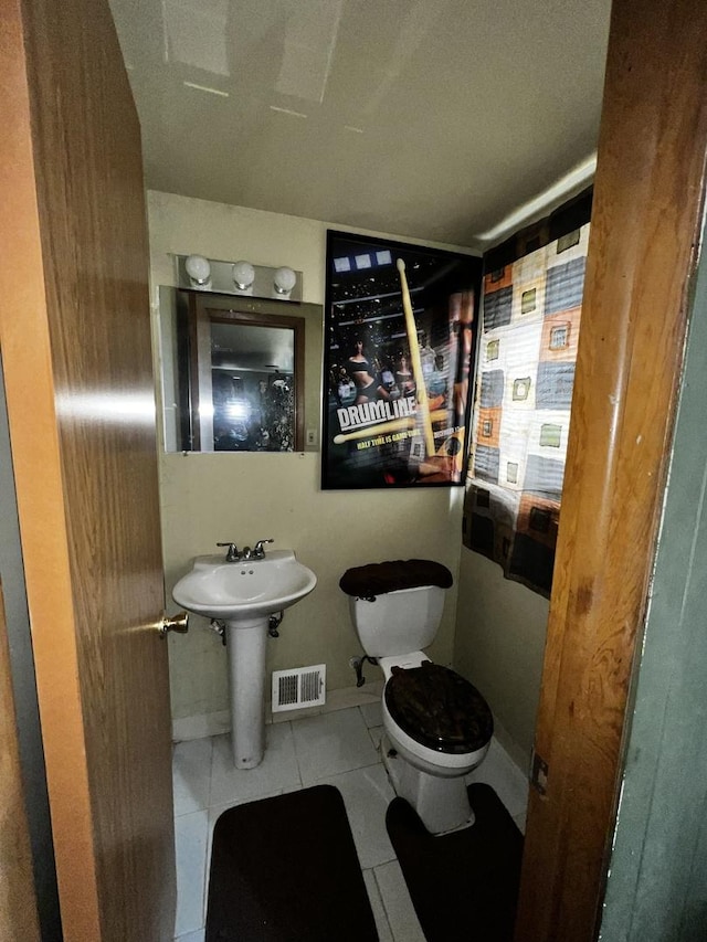 half bathroom with tile patterned flooring, baseboards, visible vents, and toilet