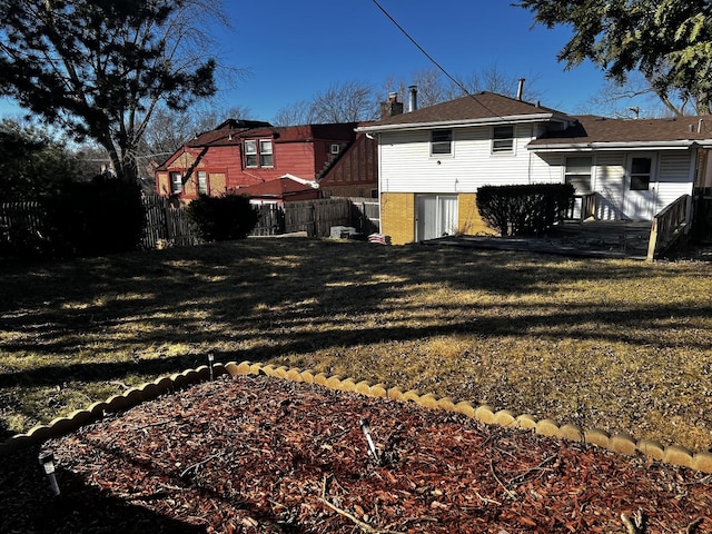 rear view of house featuring fence and a yard