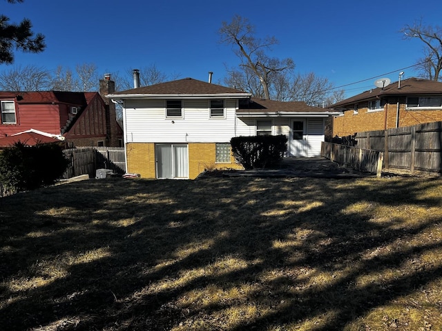 back of property featuring a fenced backyard, a yard, and brick siding