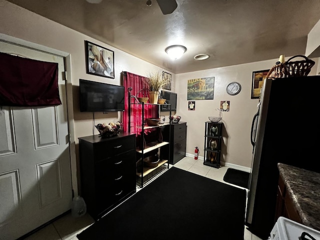 interior space with dark countertops, light tile patterned floors, baseboards, and freestanding refrigerator