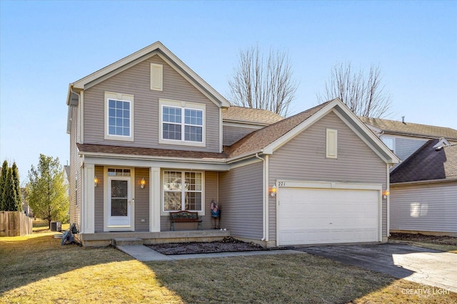 traditional-style home with a shingled roof, aphalt driveway, an attached garage, covered porch, and a front lawn