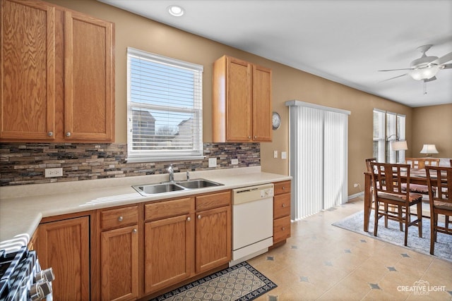 kitchen with stove, a sink, light countertops, backsplash, and dishwasher