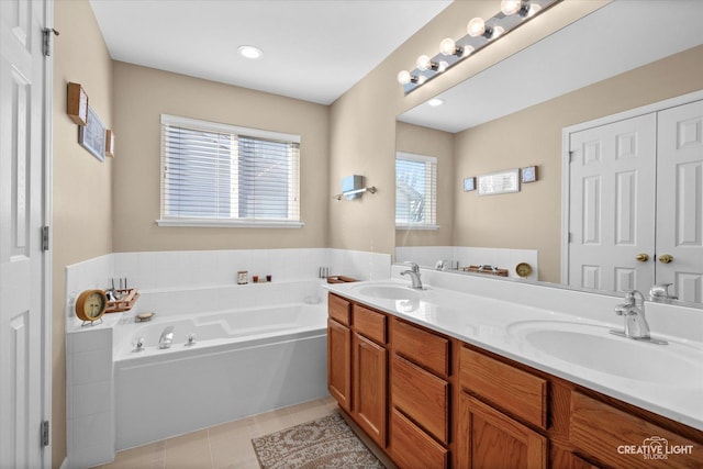 bathroom featuring tile patterned flooring, double vanity, a sink, and a bath