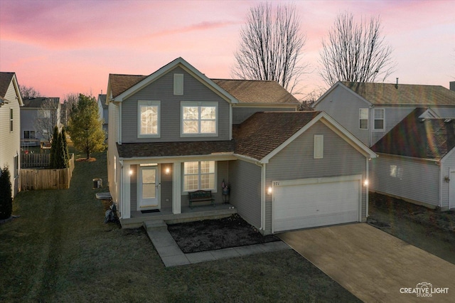 traditional-style house featuring a garage, concrete driveway, a front lawn, and fence