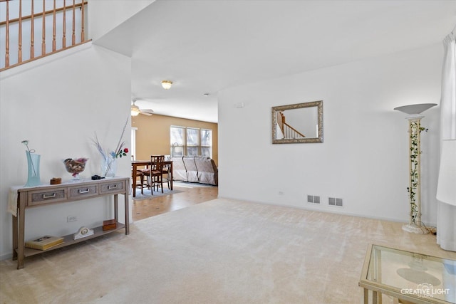 carpeted living room featuring a ceiling fan and visible vents