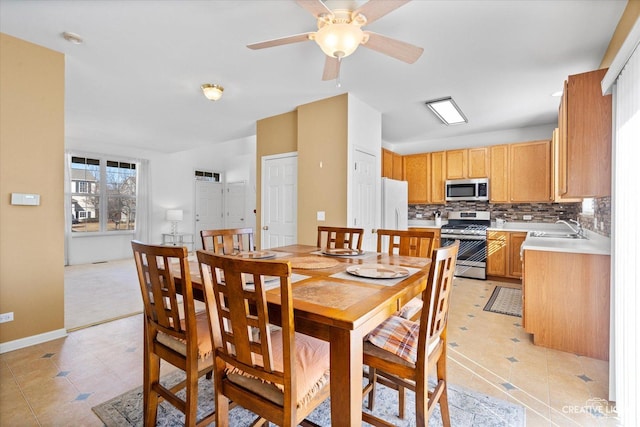 dining area featuring ceiling fan, baseboards, and light tile patterned flooring