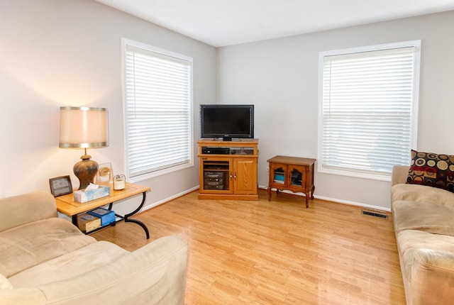 living area featuring light wood-style flooring, visible vents, and baseboards