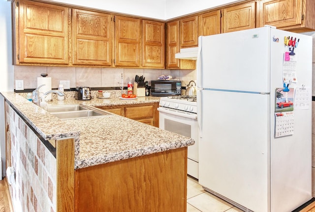 kitchen with light tile patterned flooring, a sink, a peninsula, white appliances, and under cabinet range hood