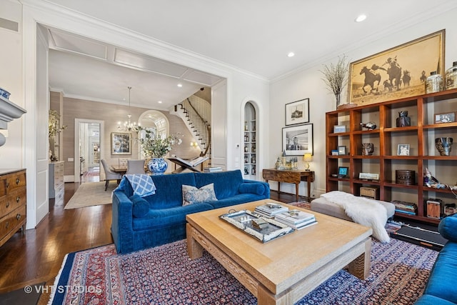 living room with stairs, an inviting chandelier, dark wood-style flooring, and crown molding