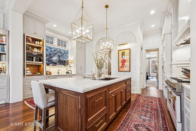 kitchen with a notable chandelier, a sink, dark wood finished floors, wall chimney exhaust hood, and stainless steel stove