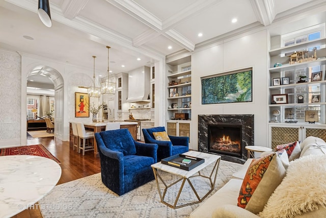 living room featuring built in shelves, beam ceiling, and crown molding