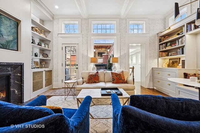 living area with beam ceiling, built in features, wood finished floors, a fireplace, and crown molding