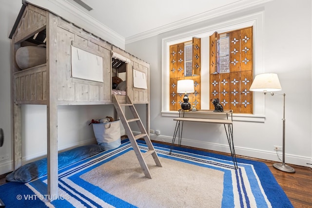 bedroom featuring visible vents, crown molding, baseboards, and wood finished floors