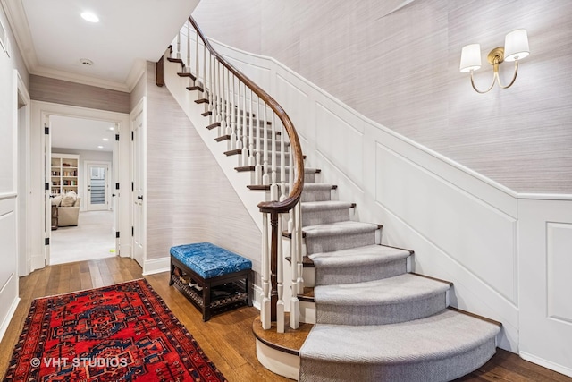 stairs with hardwood / wood-style floors, crown molding, a decorative wall, and recessed lighting