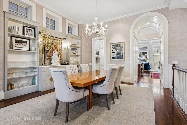 dining room with built in features, ornamental molding, wood finished floors, and a chandelier