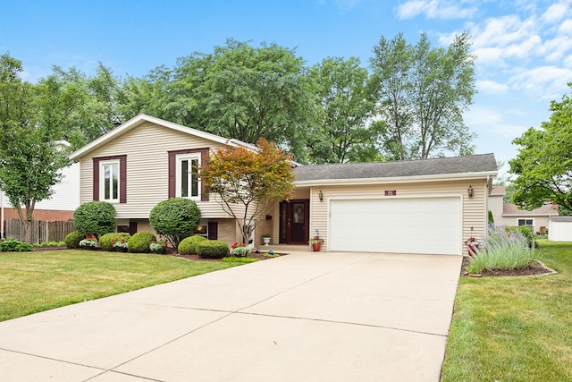 split level home featuring driveway, a front lawn, an attached garage, and fence