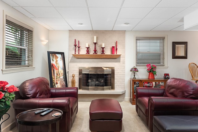 carpeted living room with a fireplace and a drop ceiling