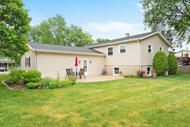 rear view of property featuring a patio area, a chimney, fence, and a lawn