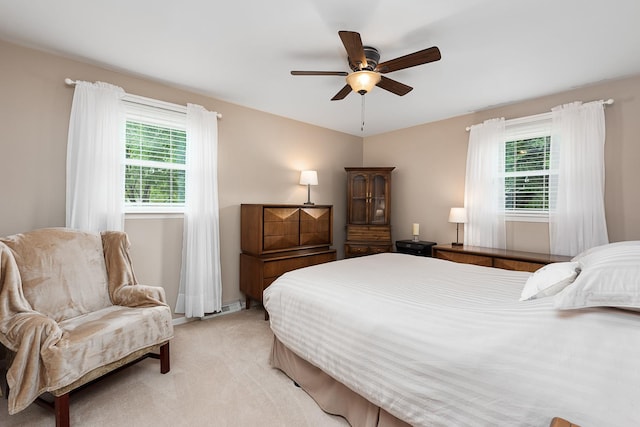 bedroom with light carpet, ceiling fan, and baseboard heating