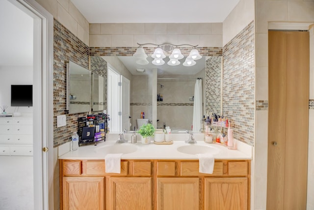 bathroom with a tile shower, a sink, tile walls, and double vanity