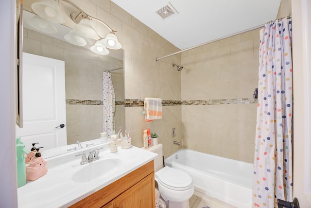 bathroom with toilet, vanity, visible vents, tile walls, and shower / bath combo