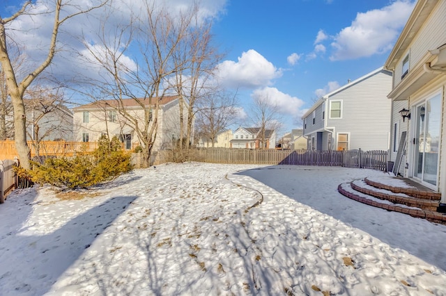 yard covered in snow with a fenced backyard and a residential view