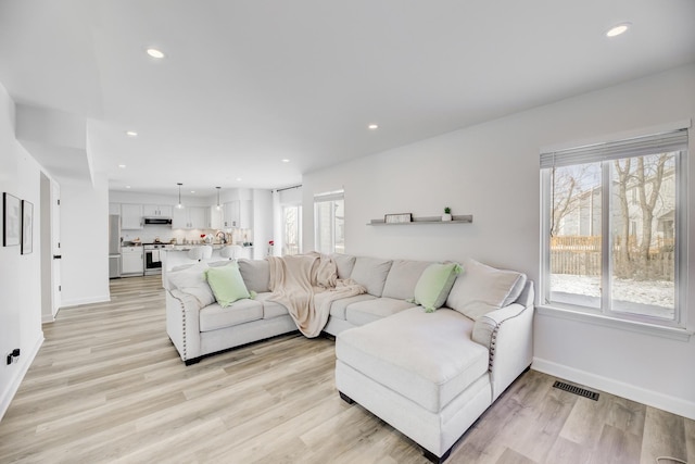 living room featuring light wood-style floors, a wealth of natural light, visible vents, and recessed lighting