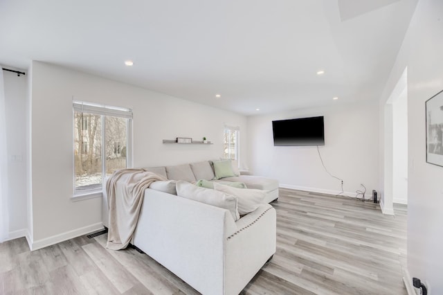 living room featuring a healthy amount of sunlight, light wood-style flooring, and baseboards