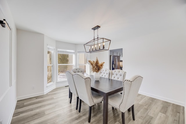 dining space featuring light wood-style floors, baseboards, and a notable chandelier