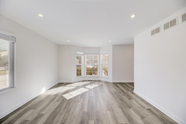 empty room featuring recessed lighting, wood finished floors, visible vents, and baseboards