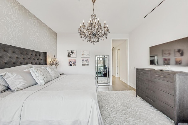 bedroom featuring an accent wall, wood finished floors, baseboards, and a chandelier