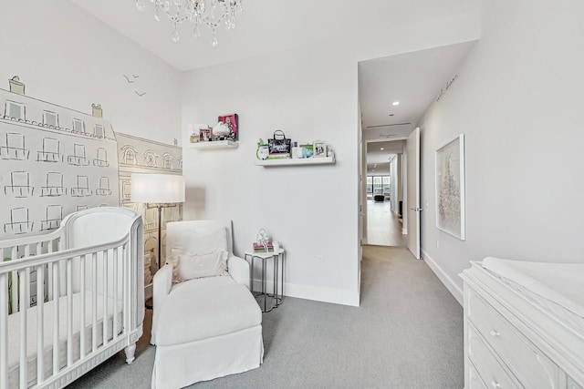 carpeted bedroom featuring baseboards, a nursery area, and an inviting chandelier