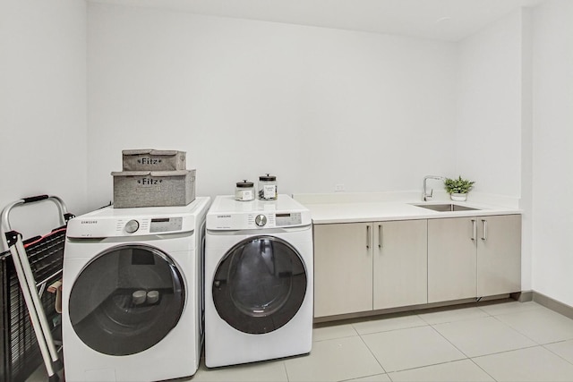 washroom with baseboards, washing machine and dryer, light tile patterned flooring, cabinet space, and a sink